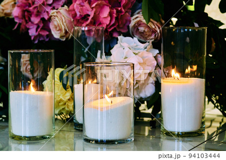 Burning candles on the background of different flowers 94103444