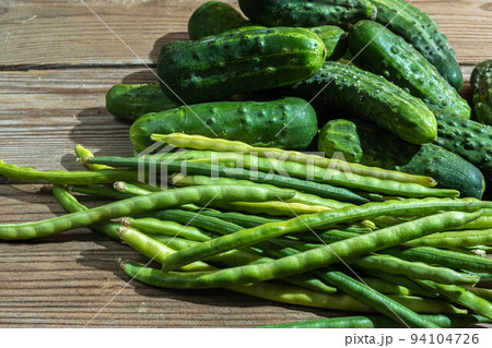 Green farm vegetables cowpea beans and cucumbers on a dark wooden 94104726