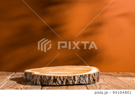 Wooden podium round saw cut of a tree on a terracotta background 94104801