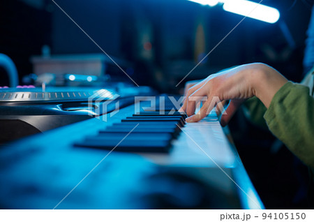 Closeup of keyboardist musician in neon light recording studio 94105150