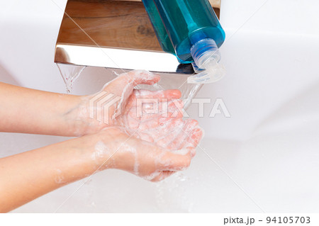 A child pours soap or antiseptic on his hands under a tap with clean water close-up on a white background. Hygiene concept. Disease prevention, health care, body care. Virus protection. A child pours soap or antiseptic on his hands under a tap with clean water close-up on a white background. Hygiene concept. Disease prevention, health care, body care. Virus protection. 94105703