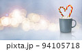 A traditional drink for a cozy winter evening. Christmas light, magic, glitter, celebration. Cocoa with marshmallows and two heart-shaped sweets in a gray cup. Glowing wave bokeh on a blue background. 94105718