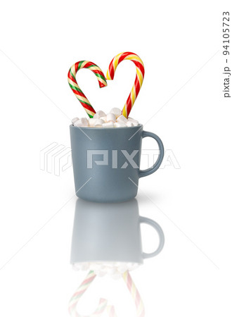 Cocoa with marshmallows and two heart-shaped Candy canes in a gray cup isolated on a white background with reflection. A Christmas gift, a traditional drink for a cozy winter evening. Cocoa with marshmallows and two heart-shaped Candy canes in a gray cup isolated on a white background with reflection. A Christmas gift, a traditional drink for a cozy winter evening. 94105723