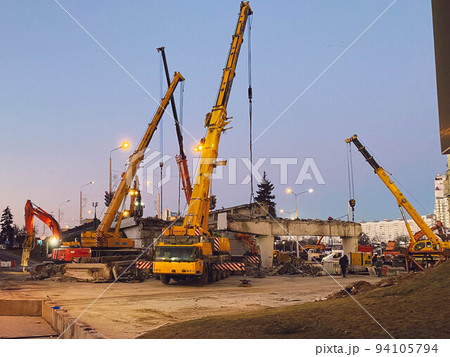construction of a broken bridge on a busy road. construction equipment on a section of the road is building an overpass, asphalt on the roads next to residential buildings 94105794