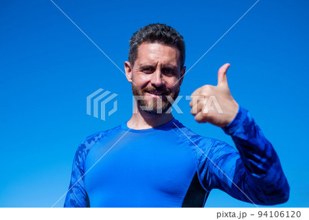 success at any cost. handsome athlete show thumb up. confident man on stadium. fitness gym outdoor. muscular athletic guy training. sport success. male fitness fashion. sportsman on sky background 94106120