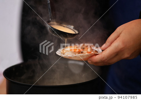 The seller pours a white sauce on the scallops 94107985