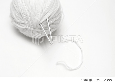ball of white wool yarn with knitting needles on white background 94112399