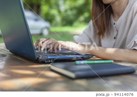 Hands pressed on the laptop keyboard on the desk outdoors in the shady atmosphere suitable for working. 94114076