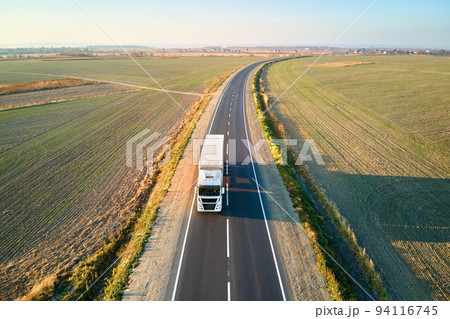 Aerial view of blurred fast moving semi-truck with cargo trailer driving on highway hauling goods in evening. Delivery transportation and logistics concept 94116745