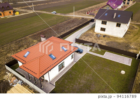 Aerial top view of house with metal shingle roof, brick chimneys and attic windows. Aerial top view of house with metal shingle roof, brick chimneys and attic windows. 94116789