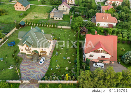 Aerial top view of house shingle roof and a car on paved yard with green grass lawn. Aerial top view of house shingle roof and a car on paved yard with green grass lawn. 94116791