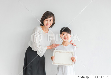 賞状を持つ笑顔の男の子と日本人女性（教師・母親） 94121363