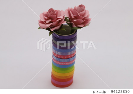 カラフルなテープを重ねて作った筒に折り紙で作ったバラの花を飾った様子 94122850