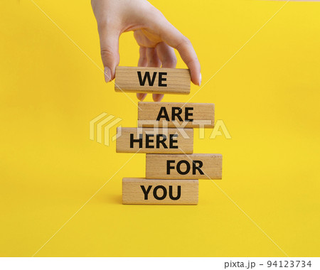 Help symbol. Wooden blocks with words 'We are here for you'. Beautiful yellow background. Businessman hand. Business and 'We are here for you' concept. Copy space. 94123734