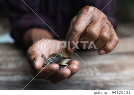 Money, Coins, Grandpa's Pension and Minimal Life Concept - Old Grandpa sadly collects a small coin on a wooden table. Money, Coins, Grandpa's Pension and Minimal Life Concept - Old Grandpa sadly collects a small coin on a wooden table. 94129258