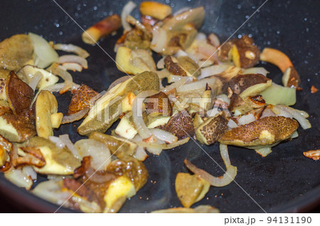 Frying edible mushrooms with onions in a pan. 94131190