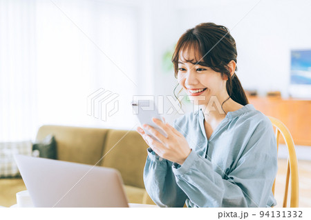 自宅でスマホとパソコンを使う女性 94131332