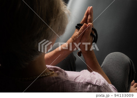 亡き人を思い手を合わす年配の女性 亡き人を思い手を合わす年配の女性 94133009