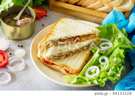Double sandwich with canned tuna and feta cheese served with lettuce leaves on a background of gray stone. 94133329