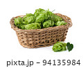 Hop cones in a straw basket on a white background. Green fresh hop cones for making beer and bread closeup. Hops are main ingredients in Beer production. 94135984