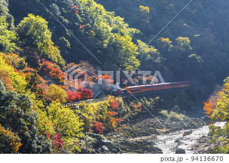 秋の保津峡を走る嵯峨野トロッコ列車と保津川下りの船 94136670