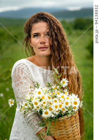 A middle-aged woman holds a large bouquet of daisies in her hands. Wildflowers for congratulations 94138932