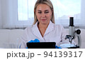 Woman scientist research chemist in a medical suit and protective gloves with a tablet computer and 94139317
