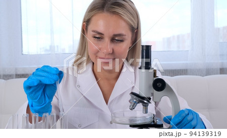 Young scientist laboratory assistant looks through a microscope in the laboratory. A young scientist 94139319