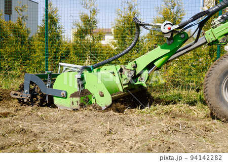 The tractor is cultivating the soil in the farm field. Freeing milling earth ground from old crops. 94142282