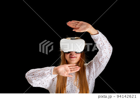 Young woman in white shirt and jeans wearing virtual helmet. Woman standing with folded hands. Young woman in white shirt and jeans wearing virtual helmet. Woman standing with folded hands. 94142621