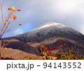 初冬、初冠雪の磐梯山とまだ黄色く紅葉した葉が残る木とのコラボレーションが綺麗 94143552