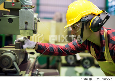 Factory worker place piece of metal into old manual machinery 94148557
