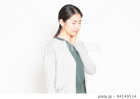 歯が痛くて頬に手を当てる女性 94149514
