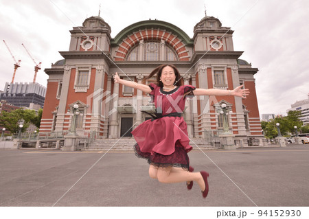 公会堂の前で跳び上がる女性 94152930
