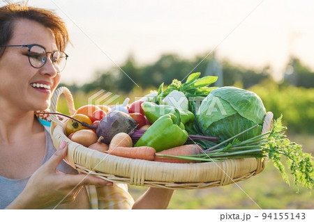 Close up basket of fresh raw organic vegetables in farmer hands Close up basket of fresh raw organic vegetables in farmer hands 94155143