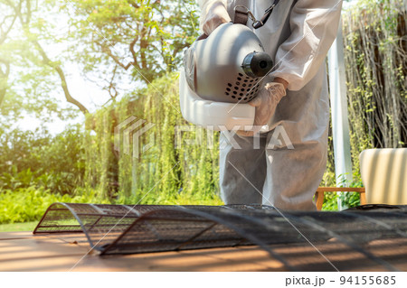 Professional technical man in prevention suit with his sterilizing machine and disinfecting water sprays the air conditioner filter for purifying coronavirus (COVID-19). Professional technical man in prevention suit with his sterilizing machine and disinfecting water sprays the air conditioner filter for purifying coronavirus (COVID-19). 94155685