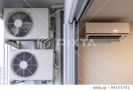 two air conditioning compressors are hung on wall. 94155701