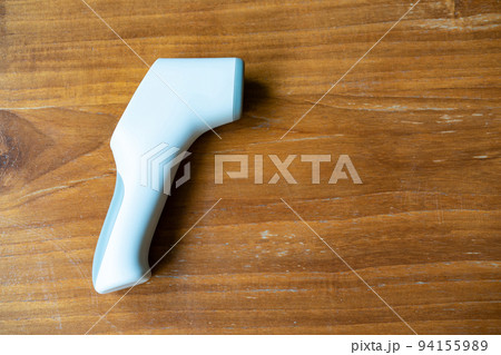 Thermometer Gun, Digital Infrared Sight Temperature Measurement Device on wood table in outdoor field. Clipping Path. 94155989