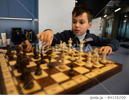 Concentrated Caucasian school boy developing chess strategy, playing board game Concentrated Caucasian school boy developing chess strategy, playing board game 94156200
