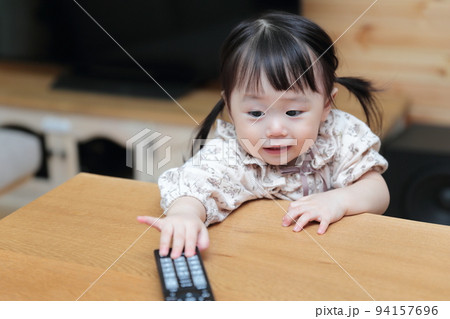 テレビのリモコンをいたずらする1歳の女の子 94157696