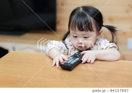 テレビのリモコンをいたずらする1歳の女の子 94157697