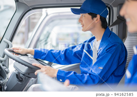 ユニフォームでトラックを運転する若い運送業者の男性社員 94162585
