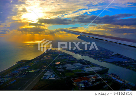 北海道・新千歳、羽田空港線、苫小牧上空の美しい夕陽と港、着陸態勢に入る飛行機の搭乗イメージ(1) 94162816