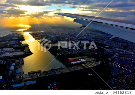 北海道・新千歳、羽田空港線、苫小牧上空の美しい夕陽と港、着陸態勢に入る飛行機の搭乗イメージ(3) 94162818