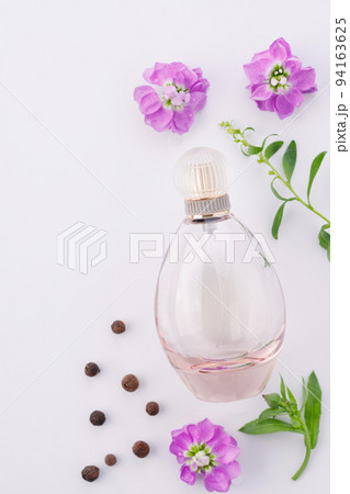 Flat lay composition. Elegant perfume on a white background with purple flowers and pepper. Ingredients and perfume. Flat lay composition. Elegant perfume on a white background with purple flowers and pepper. Ingredients and perfume. 94163625