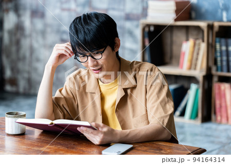 部屋で読書する眼鏡の若い男性 94164314