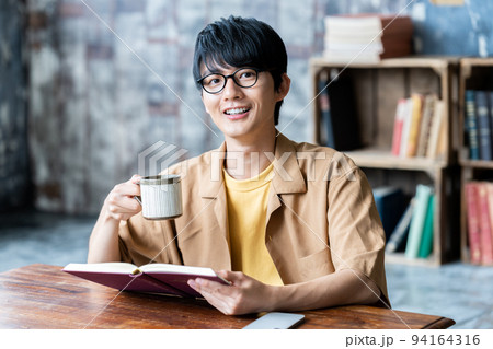 部屋で読書する眼鏡の若い男性 94164316