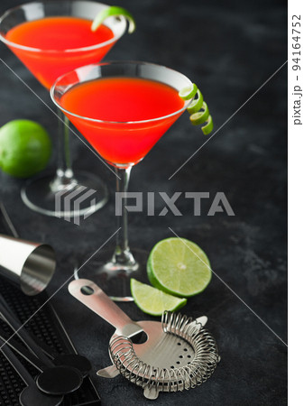 Cosmopolitan cocktail in classic crystal glasses with lime peel 94164752