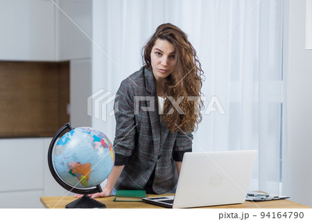 Young female teacher, travel agency worker teaches online from laptop, shows globe, tells via video call Young female teacher, travel agency worker teaches online from laptop, shows globe, tells via video call 94164790