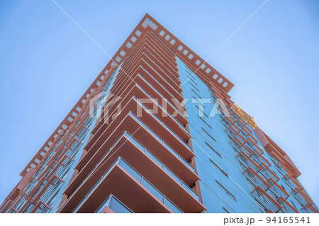 Phoenix, Arizona- Building with glass railings at the corner balconies in a low angle view Phoenix, Arizona- Building with glass railings at the corner balconies in a low angle view 94165541
